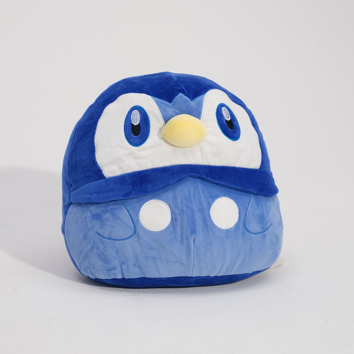 Blue plush toy with a penguin design on a light gray background